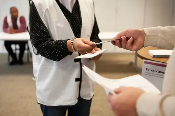 En valmottagare delar ut ett röstkort
